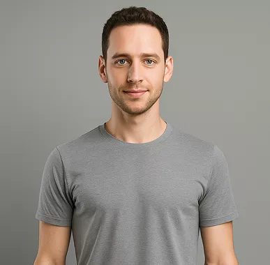 A young man with short dark hair is wearing a gray T-shirt, standing against a plain gray background. His expression is neutral and composed.